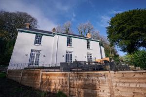 a large white house behind a brick wall at Fernhill House- Beautiful period property with 5 bedrooms and lovely views in Laugharne