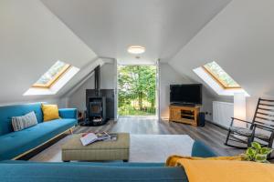 uma sala de estar com um sofá azul e uma televisão em Stylish 2 bedroom Cottage near Glasgow Airport em Lochwinnoch