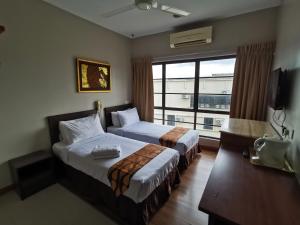 a hotel room with two beds and a window at Goodhope Hotel Shah Alam in Shah Alam