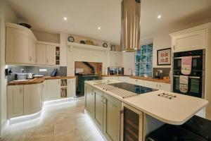 a large kitchen with white cabinets and a large island at Fernhill House- Beautiful period property with 5 bedrooms and lovely views in Laugharne