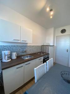 a kitchen with white cabinets and a table with chairs at Gästewohnung KL. WZL 31_7 