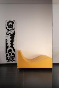 a yellow couch in front of a white wall at LHP Napoli Palace & SPA in Naples