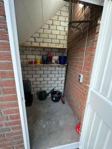 an attic room with a brick wall and a room with buckets at Haus Zuckersnuut in Dornum