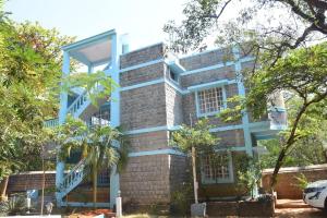 een blauw gebouw met bomen ervoor bij arulmigu sivasakthi siddhar peedam garden guest house in Tiruvannamalai