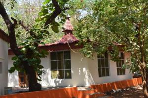 een wit huis met een rood en wit dak bij arulmigu sivasakthi siddhar peedam garden guest house in Tiruvannamalai