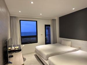 1 dormitorio con 2 camas y ventana en 窗外的海 - 海洋公園旁 en Yanliau