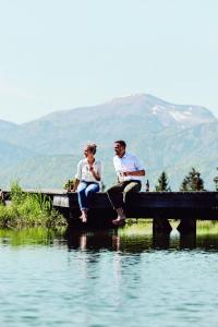 a man and woman sitting on a dock over water at Winterstellgut in Annaberg im Lammertal