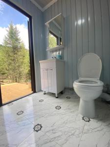 a bathroom with a white toilet and a window at Yurty Mc yurt in Dzhetyoguz