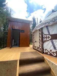 ein großes Gebäude mit einem Teppich auf einer Holzterrasse in der Unterkunft Yurty Mc yurt in Dzhetyoguz