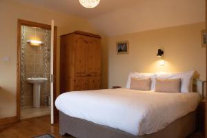 um quarto com uma grande cama branca e um lavatório em Atlantic View Cottages em Doolin