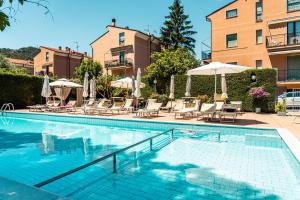a swimming pool with chairs and umbrellas next to a building at Residence Holidays in Pietra Ligure