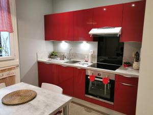 cocina con armarios rojos, fregadero y mesa en L'Horizon en Vichy