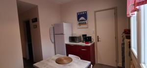 a small kitchen with a table and a white refrigerator at L'Horizon in Vichy