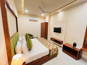 Hotel The Orchid Tree Amritsar - walking from Golden Temple في أمريتسار: غرفة فندق بسرير وتلفزيون