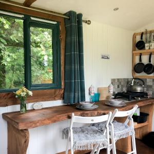 a kitchen with a table and two chairs and a window at Shire the Shepherd's Hut at Pentref Luxury Camping in Penuwch