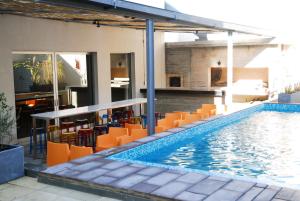 a swimming pool with orange chairs next to a building at Regency Way Montevideo Hotel in Montevideo