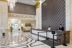 a lobby of a hotel with two people sitting at a counter at Melia Vinpearl Tay Ninh in Tây Ninh