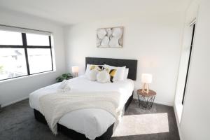 a white bedroom with a large bed with pillows at Home sweet home Christchurch Centre in Christchurch
