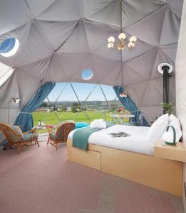 a bedroom with a tent with a bed and chairs at The Dome at Mid Auchengowan in Lochwinnoch