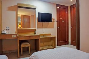 Schlafzimmer mit einem Schreibtisch, einem Spiegel und einem Bett in der Unterkunft OYO 671 Hotel Capitol in Jakarta