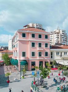 un edificio rosa con persone che lo circondano di Hotel Boka a Tirana