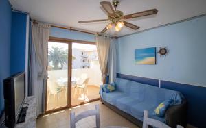 a living room with a blue couch and a ceiling fan at Primera línea Playa Romana 17 - ALBERT VILLAS in Alcossebre