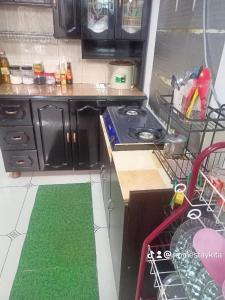 uma cozinha com um fogão e um tapete verde em Homestay KiTa malays only em Alor Setar