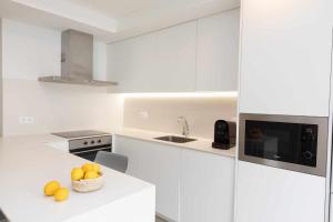 a white kitchen with a bowl of oranges on a counter at Sky Biescas I by BeValle in Biescas
