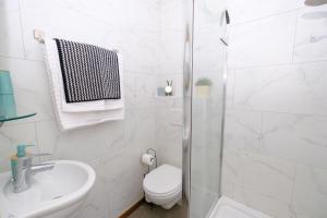 a white bathroom with a toilet and a shower at Collier's B&B in Bruges