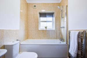 a bathroom with a tub and a toilet and a window at Beautiful 2 bedroom Apartment, Romford in Romford