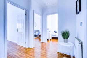 羅姆福特的住宿－Beautiful 2 bedroom Apartment, Romford，客房设有带白色墙壁和木地板的走廊。