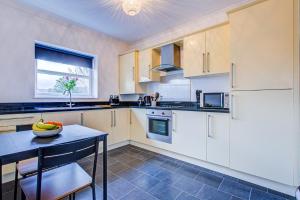 a kitchen with white cabinets and a table with a bowl of fruit at Beautiful 2 bedroom Apartment, Romford in Romford
