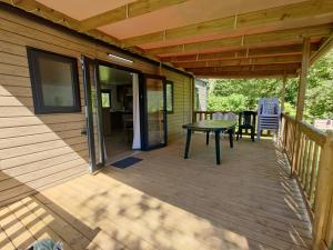 una terraza con mesa y sillas en una casa en Camping la Haie Penée ****, en Saint-Quentin-en-Tourmont