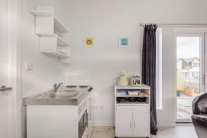 a white kitchen with a sink and a stove at Cosy and modern 1 bedroom garden house - very dog friendly! in Tarves