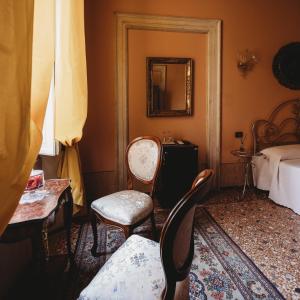 Pokój z 2 krzesłami, łóżkiem i lustrem w obiekcie Salotto delle Arti w mieście Modena