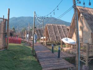 uma passagem de madeira que leva a um grupo de cabanas em Yellowstone Camps Resort Sapan em Ban Huai Ti