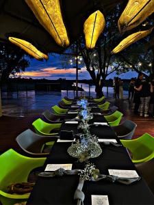 Kubu & Kwena Lodge في كاتيما موليلو: طابور طويل من الطاولات مع الكراسي الخضراء وحارق الطاولات