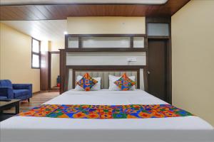 a bedroom with a large bed with a wooden headboard at FabHotel Saumendra in Varanasi