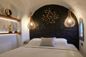 a bedroom with a bed with a stone wall at Aecon Suites in Éxo Goniá