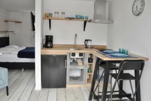 a kitchen with a table and a sink and a bed at Anna, strandhuisje dichtbij zee & strand! in Callantsoog