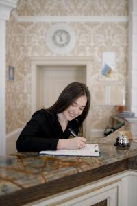 a woman sitting at a counter writing in a book at Chevalier Hotel & SPA in Bukovel