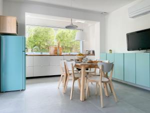 una cucina con tavolo, sedie e frigorifero blu di Appartement Océane - Villas Lake and Sea a Seignosse