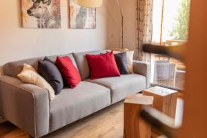 a living room with a gray couch with red pillows at Kreischberg Suites by ALPS RESORTS in Sankt Lorenzen ob Murau