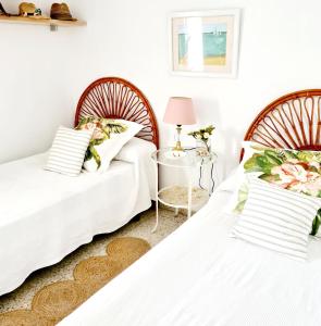 2 camas en una habitación con paredes blancas en Next to Piletas, en Sanlúcar de Barrameda