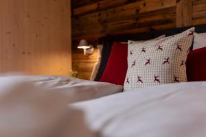 um quarto com 2 camas com lençóis brancos e almofadas vermelhas em Kreischberg Suites by ALPS RESORTS em Sankt Lorenzen ob Murau