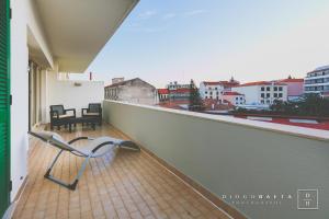 a chair on a balcony with a view of a city at This is Heaven in Funchal in Funchal