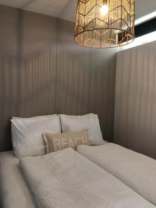 a bedroom with a white bed with a chandelier at Zee & Zand in Noordwijk