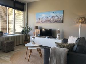 a living room with a couch and a tv and a table at Zee & Zand in Noordwijk