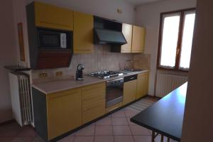 a kitchen with yellow cabinets and a stove top oven at Villa Lidia - tra il verde e l’azzurro. in San Felice del Benaco