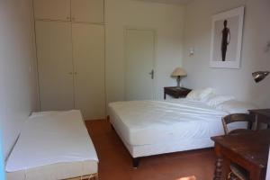 a bedroom with two beds and a table and a desk at Les Pamplemousses charmante villa proche de la mer in Porquerolles